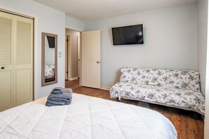 A bedroom with a bed, a sofa, a TV, and a door.
