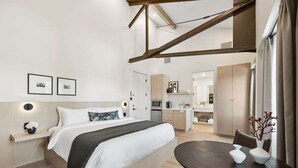 Une chambre d’hôtel moderne dotée d’un grand lit, d’une table à manger, d’un coin cuisine et d’une salle de bain.