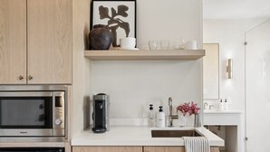 Une cuisine moderne équipée d’un four à micro-ondes, d’une machine à café et d’un espace lavabo avec des articles de toilette.