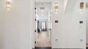 A hotel hallway with a modern design, featuring a light-colored floor, white walls, and numbered doors. - Casa Iglesia Studio 211 (Santa Barbara)