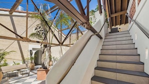 A staircase leading to an upper level, surrounded by a checkered floor, with a palm tree and a sofa in the foreground. - Casa Iglesia Studio 204 (Santa Barbara)