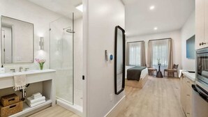 A modern hotel room with a shower, a vanity with a mirror, a sofa, and a dining area. - Casa Iglesia Studio 204 (Santa Barbara)