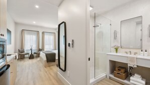A modern hotel room with a kitchenette, a dining area, a large mirror, a shower area, and a bathroom with a vanity and storage. - Casa Iglesia Studio 209 (Santa Barbara)