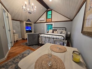 Ein Schlafzimmer mit Bett, Schreibtisch, Fernseher und einer Kristallleuchter.