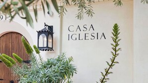 Una pared con el texto 'CASA IGLESIA', una puerta de madera y un farol.