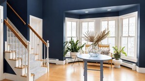 Un interior moderno con una escalera que conduce a una unidad privada, un área de entrada compartida y ventanas amplias.