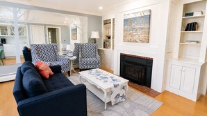Una sala de estar con sofá, sillones, chimenea y estantería.