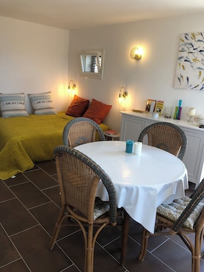 Ein Schlafzimmer mit einem Bett, zwei Kissen, einem Nachttisch, einem Fenster und einer Wandleuchte.