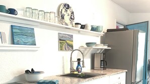 A kitchen with white cabinets, a stainless steel refrigerator, a sink with a faucet, and a countertop with a dish soap bottle. - Serene- pool house with large enclosed oasis of local artist in Port Charlotte (Port Charlotte)