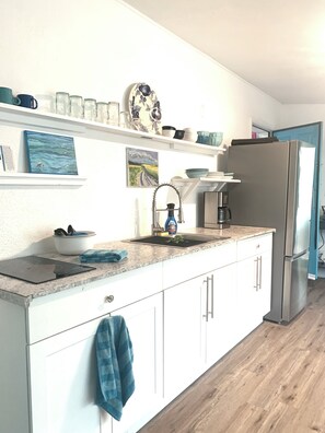 A kitchen with white cabinets, a stainless steel refrigerator, a sink with a faucet, and a countertop with a dish soap bottle. - Serene- pool house with large enclosed oasis of local artist in Port Charlotte (Port Charlotte)