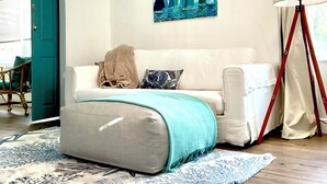 A room with a sofa, a throw blanket, a painting, a lamp, and a patterned rug. - Serene- pool house with large enclosed oasis of local artist in Port Charlotte (Port Charlotte)