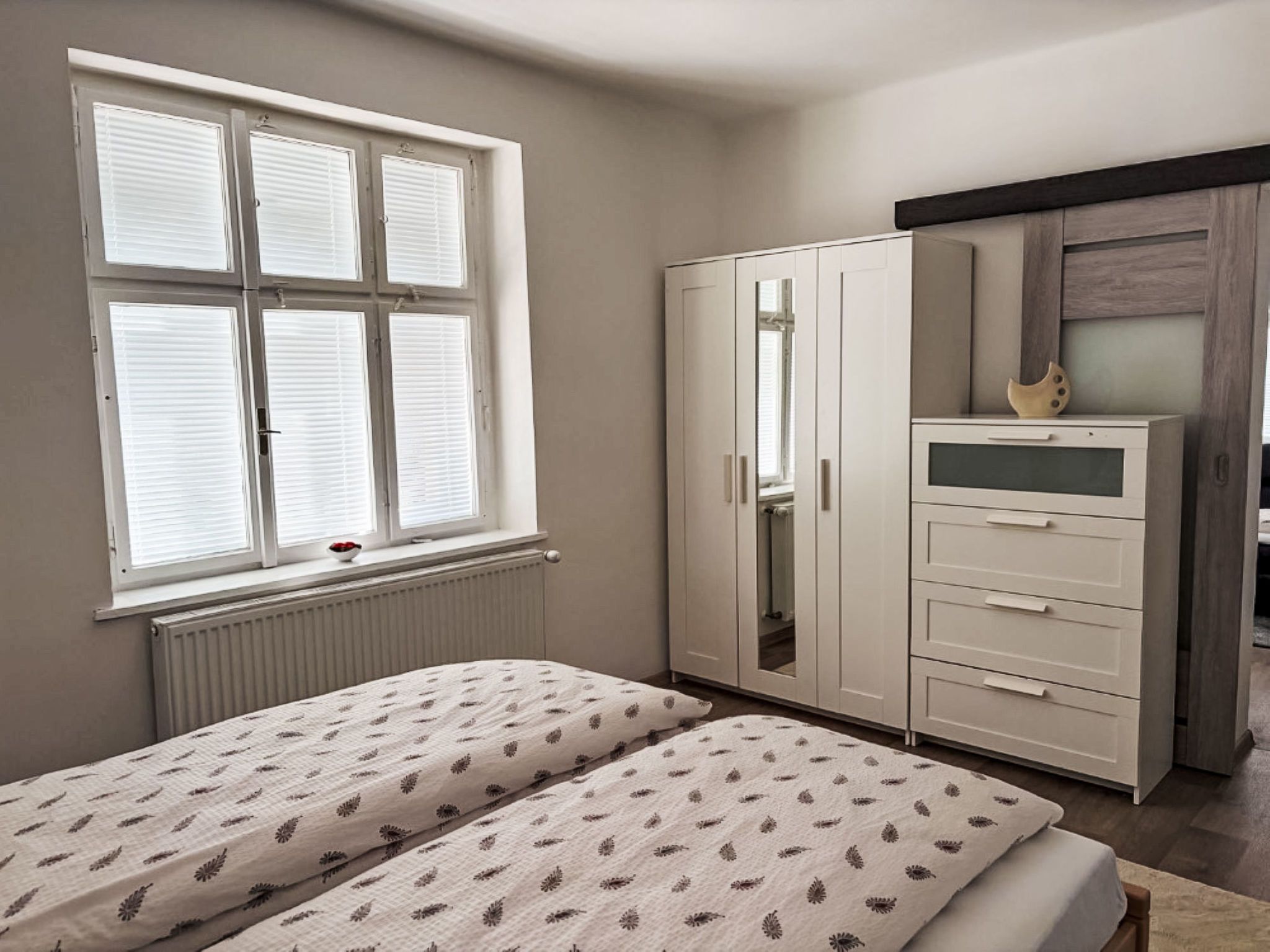 Un dormitorio con dos camas, un armario y una ventana con persianas.