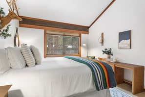 Un dormitorio con una cama grande, una ventana, un escritorio y una planta.