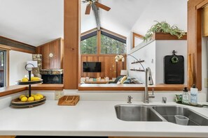 Una cocina moderna con un ventanal grande, vigas de madera, televisión empotrada y un lavamanos.