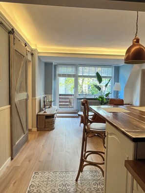 Eine Küche mit einer Holzausziehtheke, einer hängenden Pendelleuchte und Blick durch das Fenster.