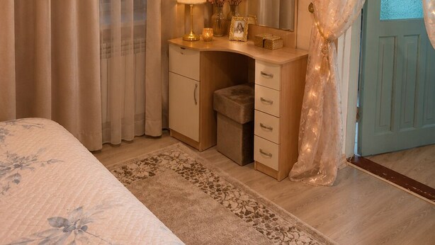 Un dormitorio con cama, tocador con espejo, lámpara y cómoda.