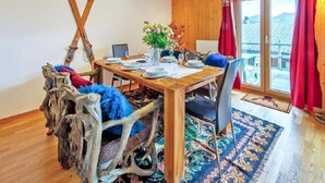 Un comedor con mesa de madera, sillas y vista a través de un ventanal.