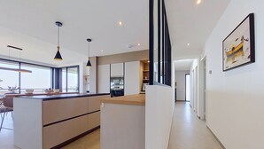 Een moderne keuken met een centraal eiland, hanglampen en uitzicht naar buiten.
