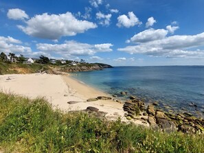 A coastal beach with clear skies, rocky shoreline, and houses in the background. - 4 Mouettes by Interhome (Locmaria-Plouzané)