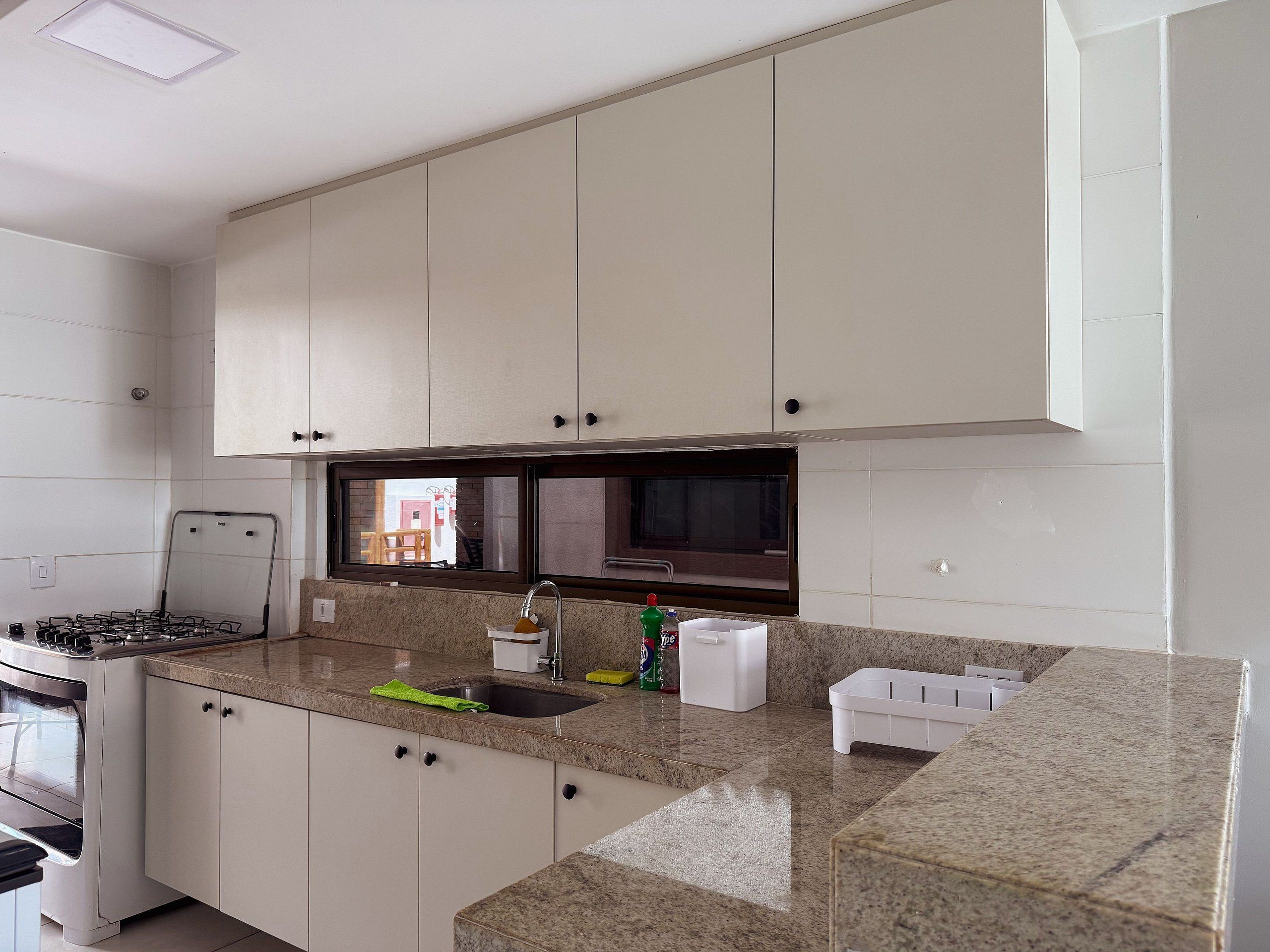 A kitchen with white cabinets, a granite countertop, a stove, and a window.
