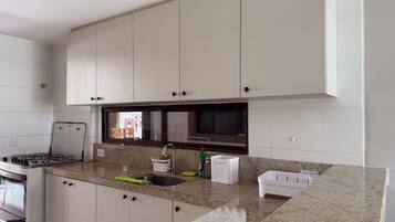 A kitchen with white cabinets, a granite countertop, a stove, and a window.