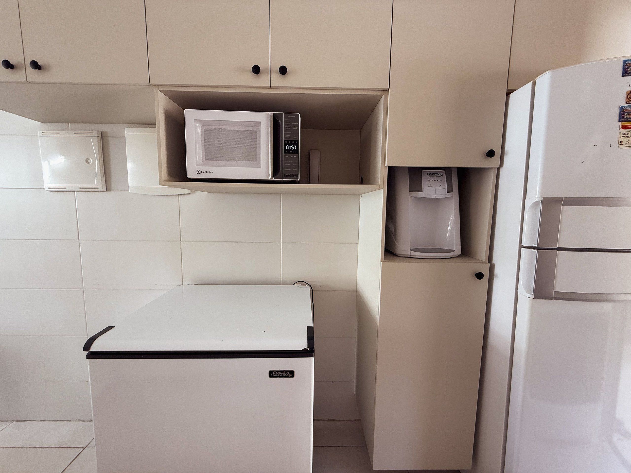 Una kitchenette compacta con microondas, cafetera y refrigerador pequeño.