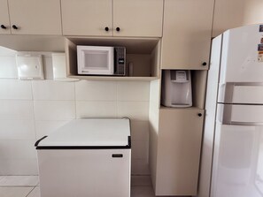 Eine kompakte Küchenzeile mit Mikrowelle, Kaffeemaschine und einem kleinen Kühlschrank.