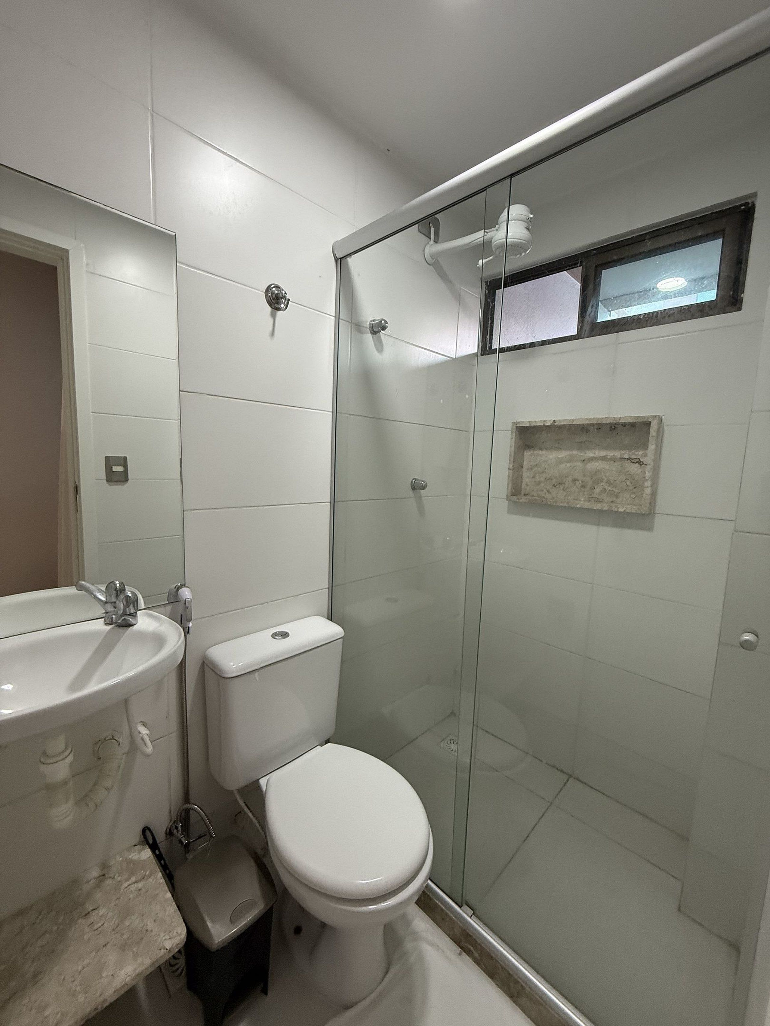 A bathroom with a toilet, sink, and glass shower enclosure.