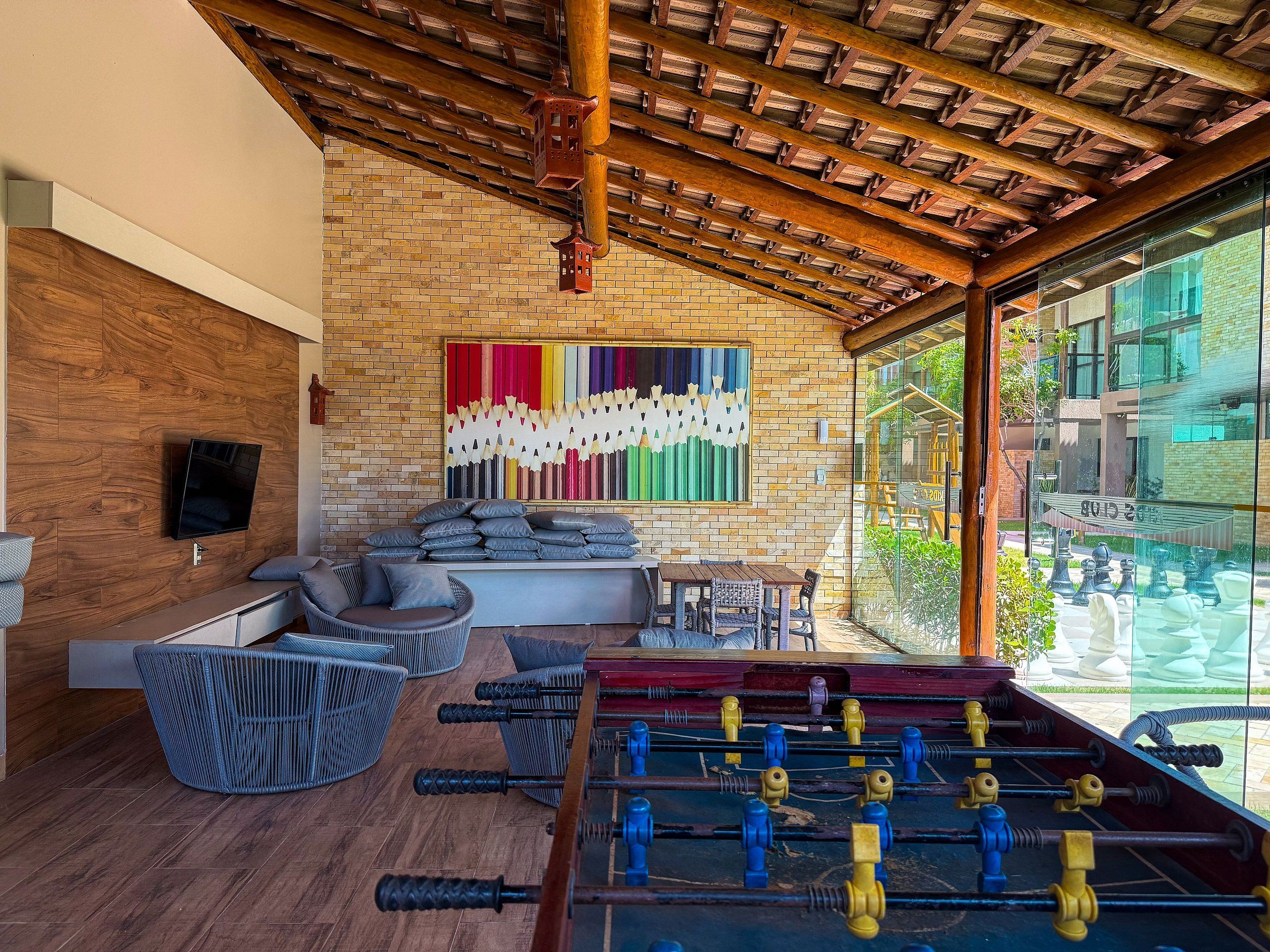 Une pièce avec un mur en briques, un plafond en bois, un canapé, une table et une table de baby-foot.
