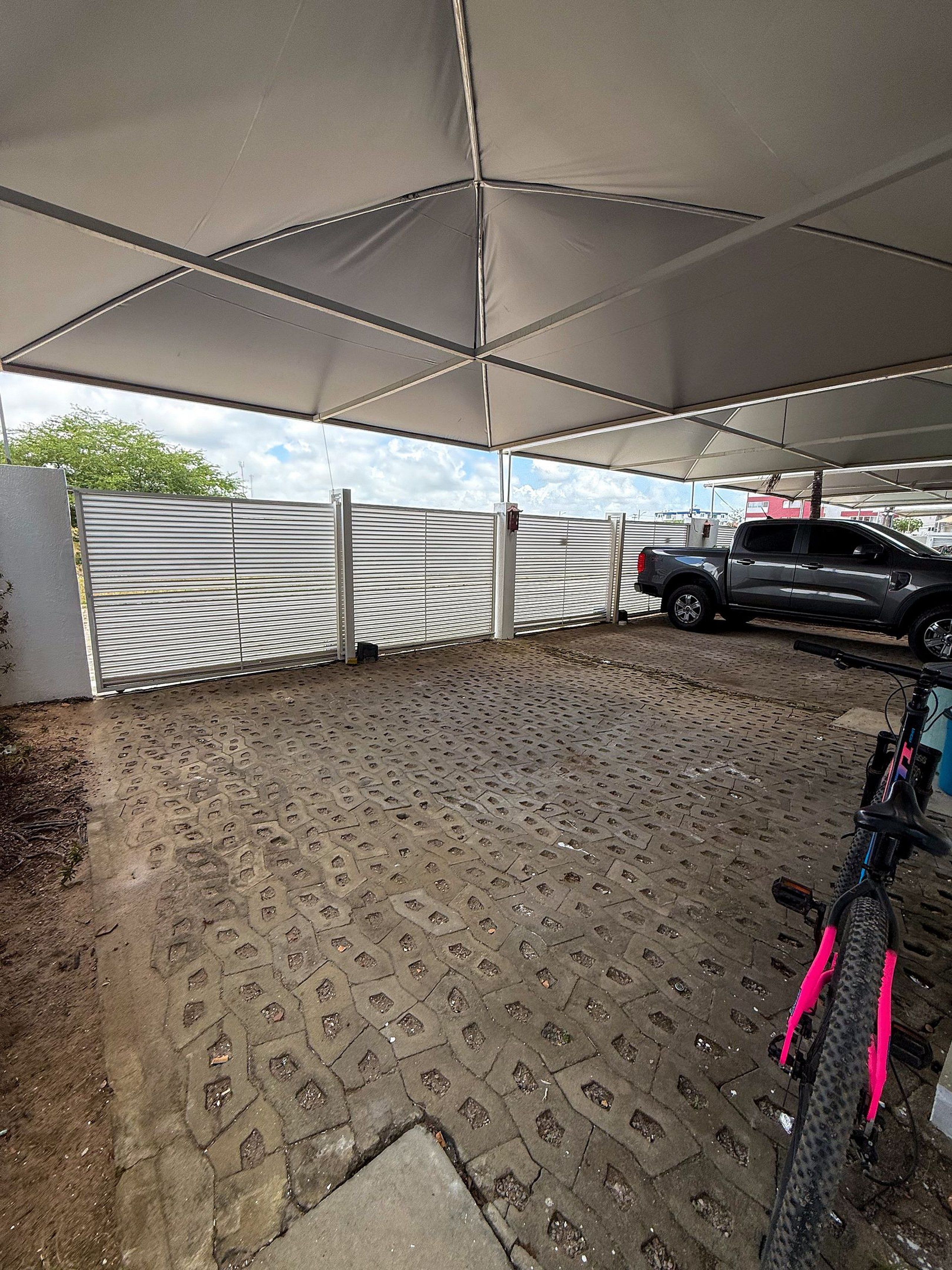 Un espace extérieur abrité, doté d’un sol pavé, d’un vélo et d’un véhicule garé.