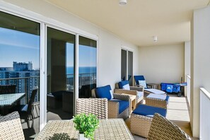 A balcony with wicker furniture, a table, and a potted plant. - Ariel Dunes I 1909- The Radiant Vista (Miramar Beach)