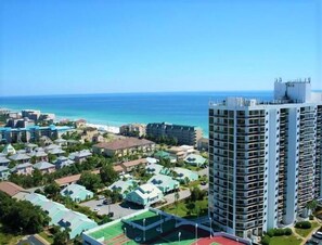 A coastal resort area with a high-rise building, smaller residential buildings, and a beach. - Ariel Dunes I 1909- The Radiant Vista (Miramar Beach)