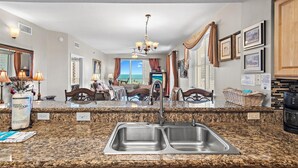 A kitchen with granite countertops, stainless steel sinks, and a chandelier. - Ariel Dunes I 610- Emerald Eden (Miramar Beach)