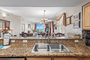 A kitchen with granite countertops, stainless steel sinks, and a chandelier. - Ariel Dunes I 610- Emerald Eden (Miramar Beach)