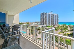 A balcony with a view of a tall building, a pool, and a clear blue sky. - Ariel Dunes I 610- Emerald Eden (Miramar Beach)
