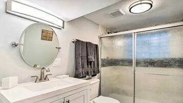A bathroom with a white sink, a mirror, a towel rack, and a glass shower enclosure.