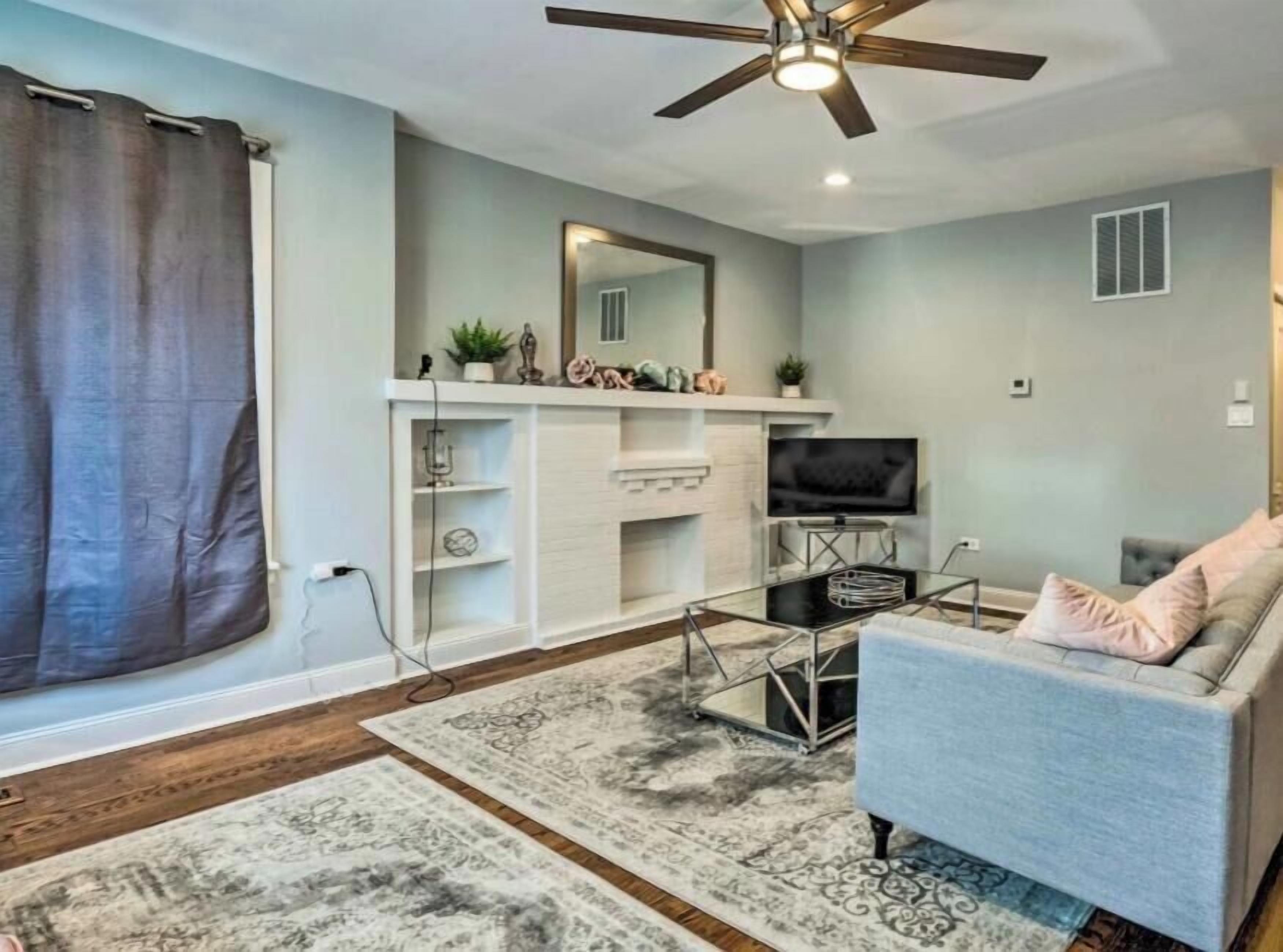 A living room with a ceiling fan, a TV, a sofa, and a fireplace.