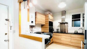 Een moderne keuken met houten kastjes, een zwart aanrecht en hanglampen.