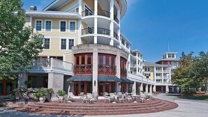 A multi-story hotel with a curved facade, outdoor seating area, and a central courtyard. - Bahia 4423- Changes in Latitudes (Miramar Beach)