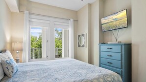 A bedroom with a bed, a dresser, a television, and a balcony with a view. - Bahia 4423- Changes in Latitudes (Miramar Beach)