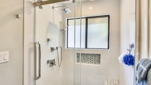 Eine gläserne Dusche mit Milchglasfenster, ein Handtuchhalter und ein sichtbares Bedienfeld.