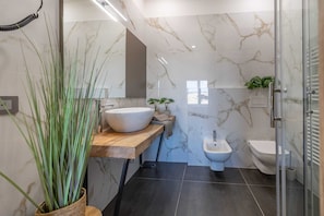 Ein modernes Badezimmer mit großem Spiegel, einem Aufsatzwaschbecken, einem Bidet und einer Duschkabine.