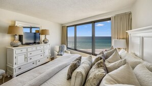 Una camera d'albergo con un letto grande, una televisione, una cassettiera e vista sull'oceano.