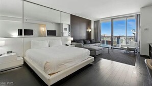 A modern hotel room with a large bed, a sofa, a TV, and a balcony with a city view. - Palms Place Hotel HighFloor StripView with Balcony (Las Vegas)