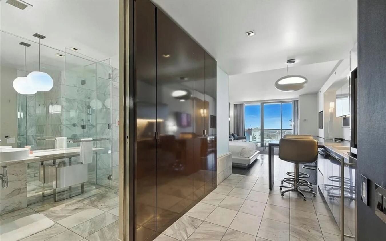 Een moderne badkamer met glazen douchedeuren, een marmeren wastafel en een grote spiegel.