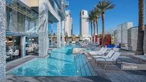 A pool area with lounge chairs, a bar, and a tall building labeled 'PALMS' in the background. - Palms Place Hotel HighFloor StripView with Balcony (Las Vegas)