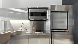 A modern kitchen with stainless steel appliances, a built-in microwave, and a refrigerator. - Palms Place Hotel HighFloor StripView with Balcony (Las Vegas)