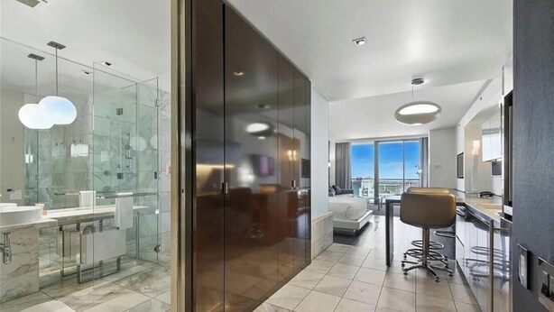 A modern hotel room with a glass shower, a bed, a dining area, and a view of the city. - Palms Place Hotel HighFloor StripView with Balcony (Las Vegas)