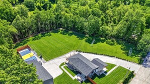 An aerial view of a residential property with a large house, a tennis court, and surrounding greenery. - The Stadium by Mercer Stays | Private 2.2Acre Sports Estate for Teams & Families (Saint Charles)