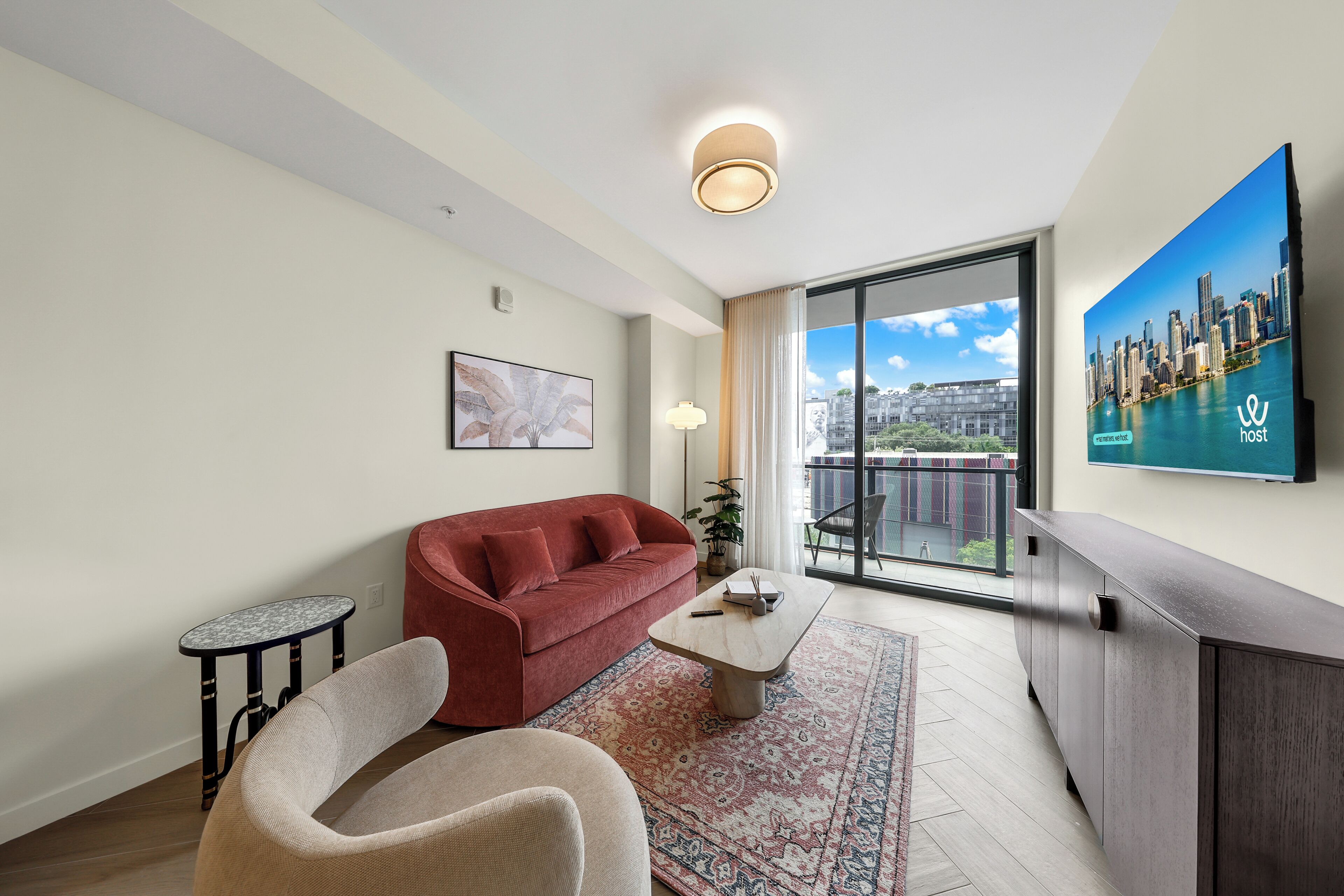 A modern living room with a red sofa, a coffee table, a TV, and a city view.